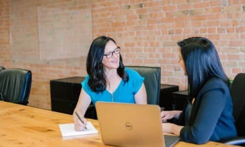 Deux personnes discutant autour d'une table, représentant la gestion de la base clients avec Sage et Wise-Up